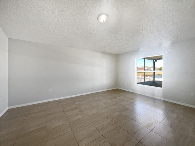 unfurnished room featuring dark tile patterned floors and a textured ceiling