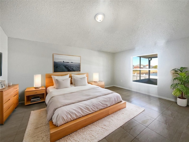 bedroom with dark tile patterned flooring and a textured ceiling