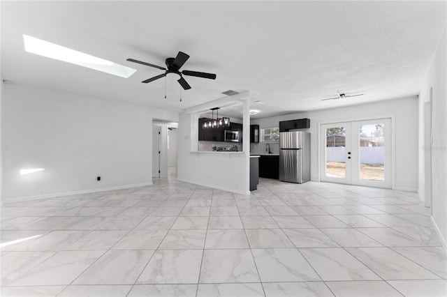 unfurnished living room featuring french doors, ceiling fan, and a skylight