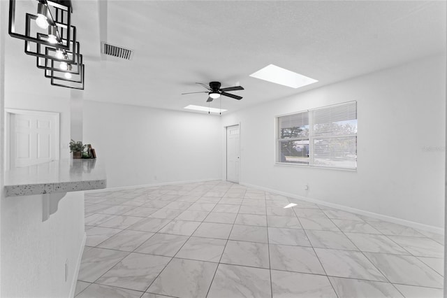 unfurnished room with ceiling fan and a skylight