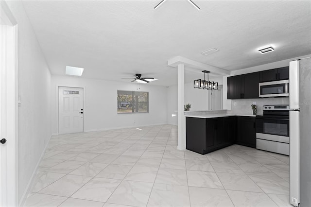 kitchen with ceiling fan with notable chandelier, decorative light fixtures, kitchen peninsula, stainless steel appliances, and a textured ceiling