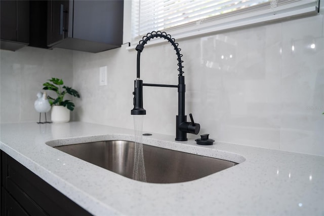 room details with tasteful backsplash, light stone countertops, and sink