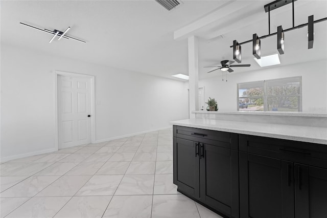 kitchen with light stone counters, ceiling fan, and a skylight