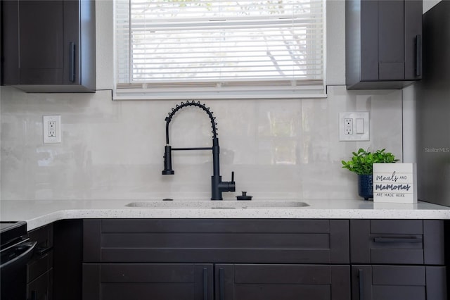 kitchen featuring light stone countertops, sink, decorative backsplash, and electric range