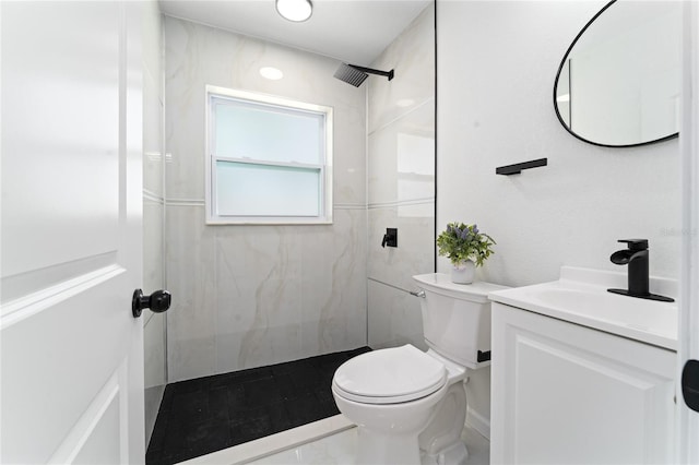 bathroom with vanity, a tile shower, and toilet