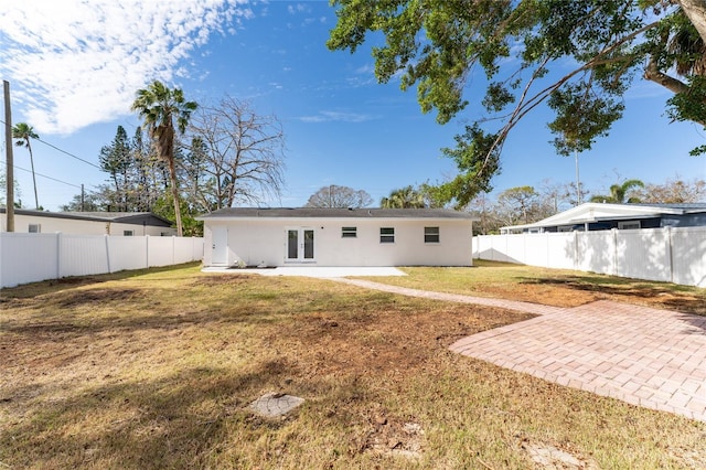 back of house with french doors, a lawn, and a patio area