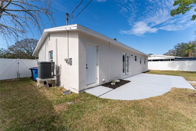 back of property with central AC, a patio, and a lawn