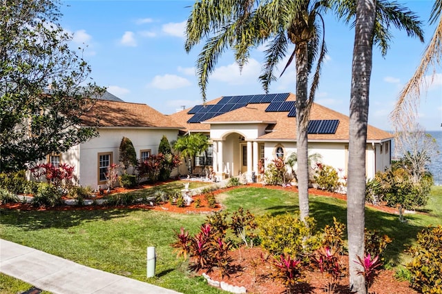 mediterranean / spanish house with a front lawn and solar panels