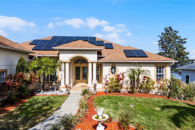 mediterranean / spanish-style house with french doors, a front yard, and solar panels