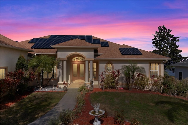 view of front of property with a lawn, french doors, and solar panels