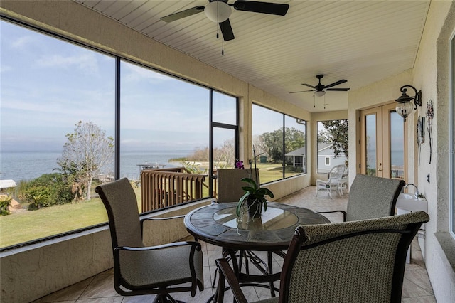 sunroom / solarium with ceiling fan and a water view