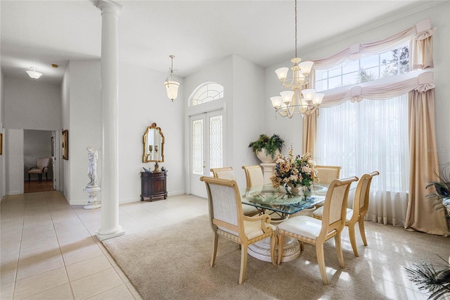 tiled dining room featuring an inviting chandelier, a high ceiling, french doors, and ornate columns