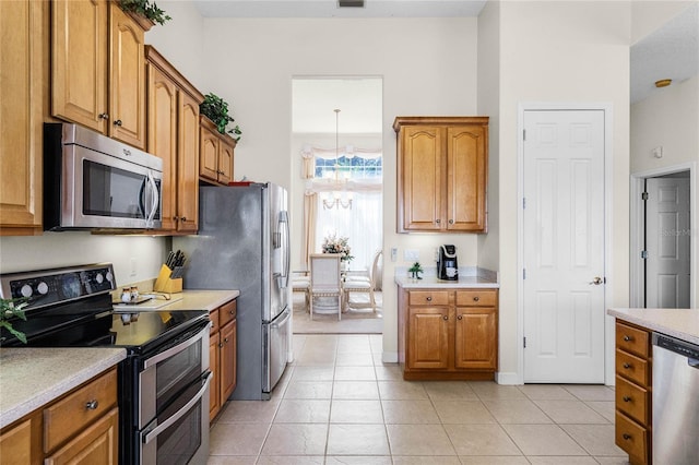 kitchen featuring appliances with stainless steel finishes, light tile patterned floors, and a notable chandelier