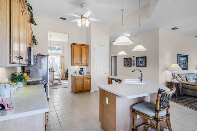 kitchen featuring light tile patterned flooring, sink, a center island with sink, pendant lighting, and stainless steel appliances