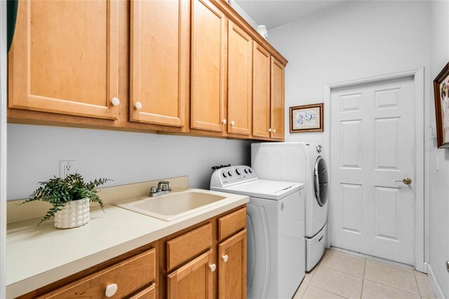 washroom featuring sink, washer and clothes dryer, cabinets, and light tile patterned flooring