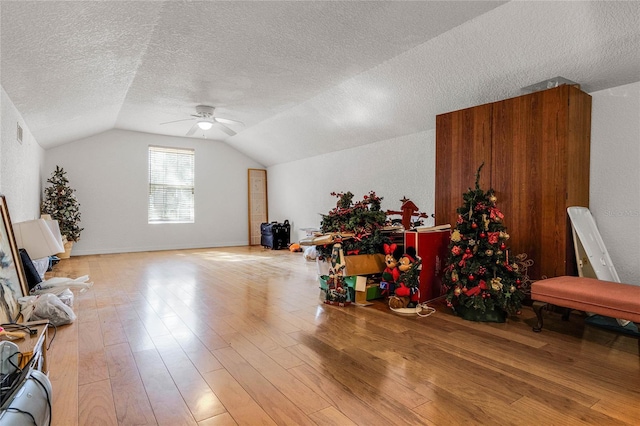 additional living space featuring vaulted ceiling, hardwood / wood-style floors, ceiling fan, and a textured ceiling