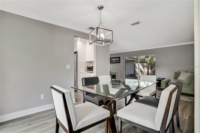 dining room featuring crown molding, a chandelier, and light hardwood / wood-style floors