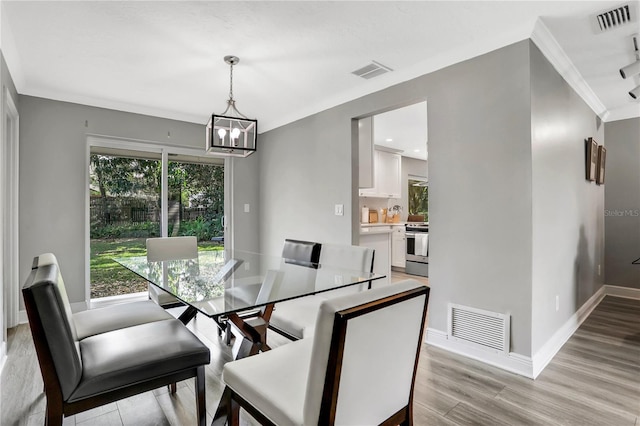 dining room featuring crown molding, light hardwood / wood-style flooring, and a notable chandelier