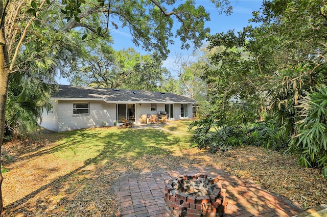 back of house featuring a fire pit, a patio area, and a lawn