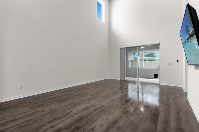 interior space featuring a towering ceiling, plenty of natural light, and dark hardwood / wood-style floors