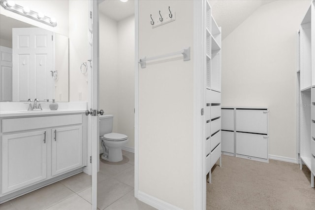 bathroom with vanity, lofted ceiling, tile patterned floors, and toilet