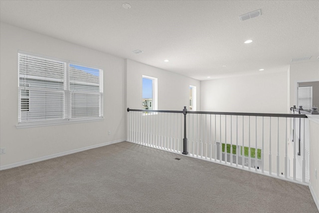 unfurnished room featuring a healthy amount of sunlight, carpet floors, and a textured ceiling