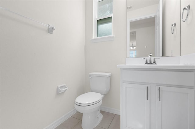 half bathroom with toilet, vanity, baseboards, and tile patterned floors