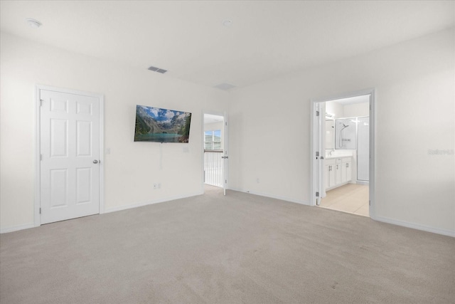 interior space with light colored carpet, visible vents, baseboards, and ensuite bathroom