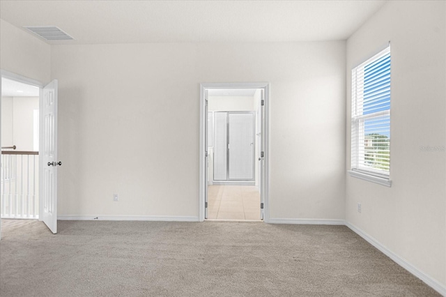 empty room with baseboards, visible vents, and light colored carpet