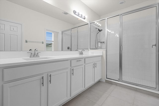 full bath with double vanity, a stall shower, tile patterned flooring, and a sink