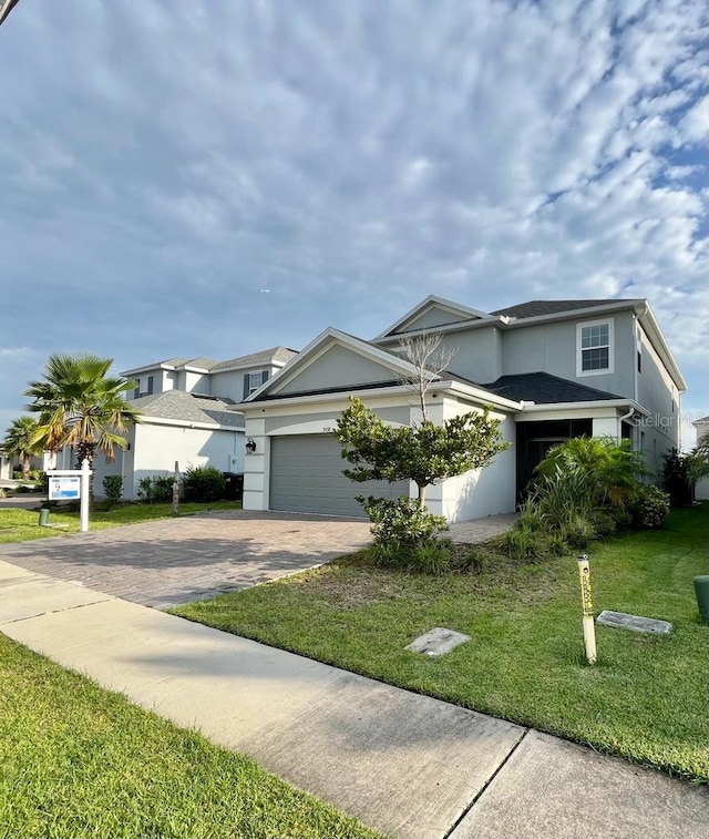 view of front of property featuring a front yard, decorative driveway, an attached garage, and stucco siding