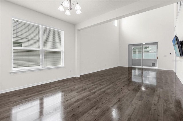 interior space featuring baseboards, dark wood-type flooring, and a notable chandelier