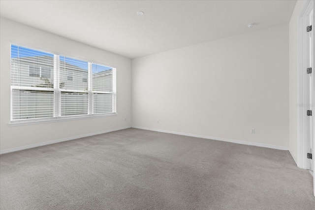 unfurnished room featuring light carpet and baseboards