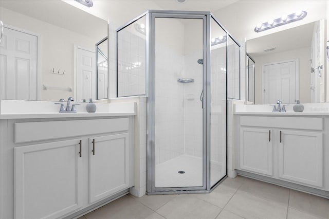 full bathroom with two vanities, a stall shower, tile patterned flooring, and a sink