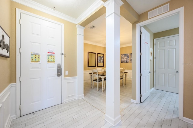 entryway with ornate columns, crown molding, and light wood-type flooring