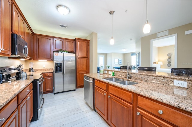 kitchen featuring appliances with stainless steel finishes, decorative light fixtures, light stone countertops, and sink