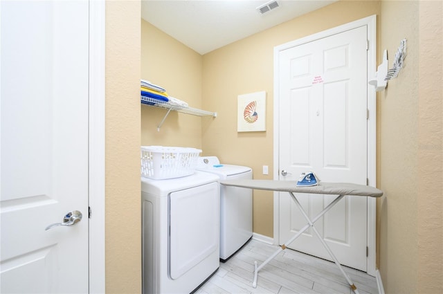 laundry room with independent washer and dryer and light wood-type flooring