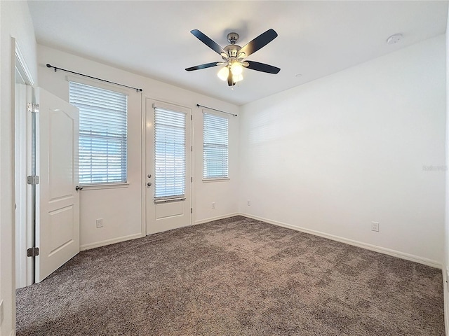 empty room featuring ceiling fan and dark colored carpet