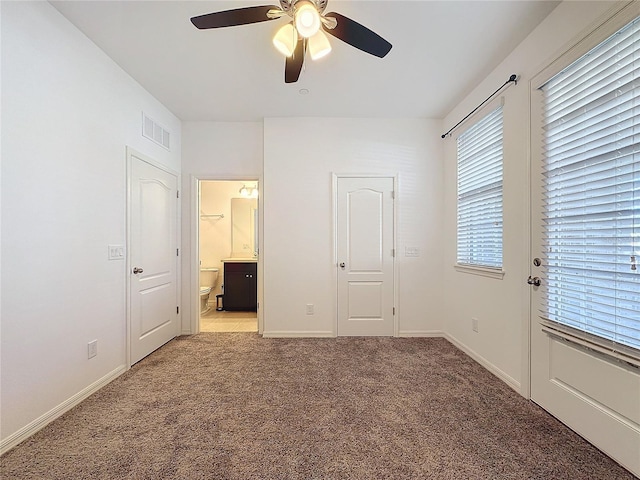 unfurnished bedroom featuring ceiling fan, light colored carpet, and ensuite bathroom