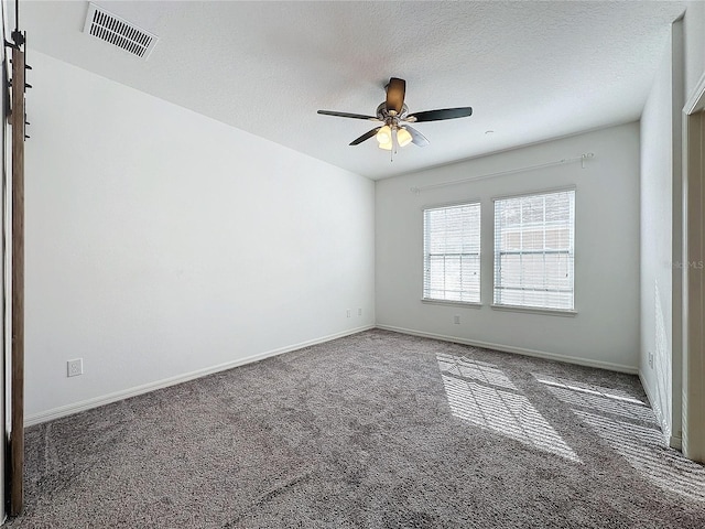 carpeted empty room featuring ceiling fan and a textured ceiling