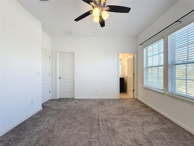 unfurnished bedroom with ceiling fan, light colored carpet, and ensuite bath