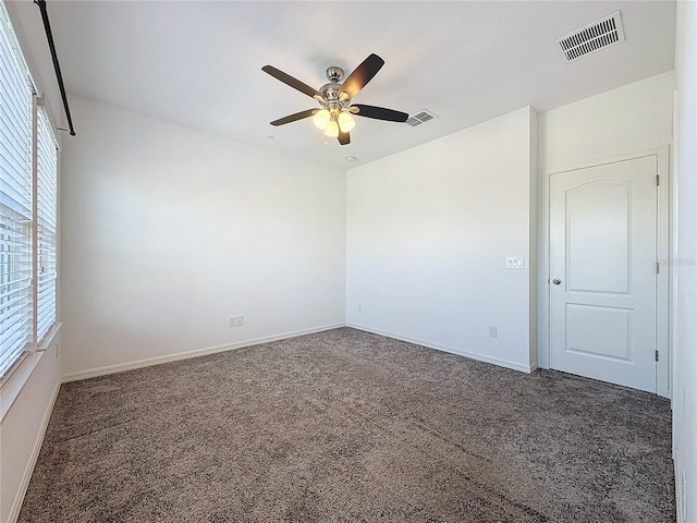 unfurnished room with ceiling fan and dark colored carpet