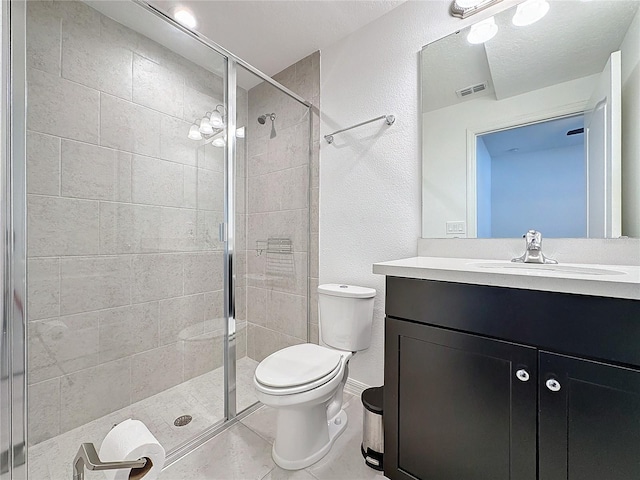 bathroom featuring a shower with door, vanity, tile patterned flooring, and toilet