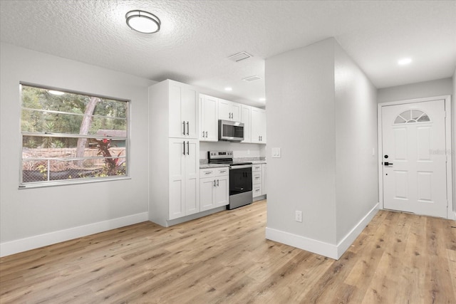 kitchen featuring stainless steel appliances, a textured ceiling, white cabinets, and light wood-type flooring