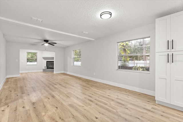 unfurnished living room with ceiling fan, a textured ceiling, and light wood-type flooring