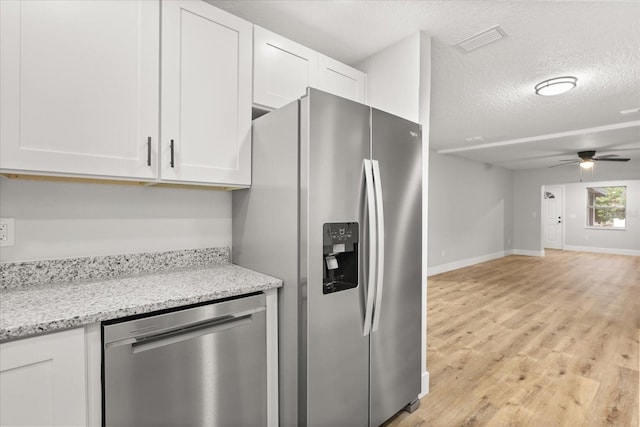 kitchen featuring appliances with stainless steel finishes, white cabinets, ceiling fan, light stone counters, and a textured ceiling