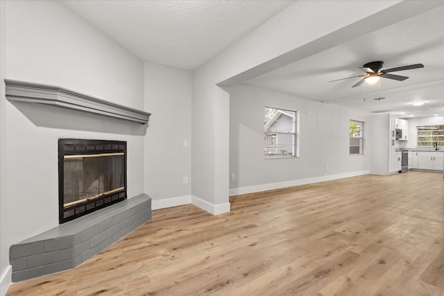 unfurnished living room featuring ceiling fan, light hardwood / wood-style floors, sink, and a textured ceiling