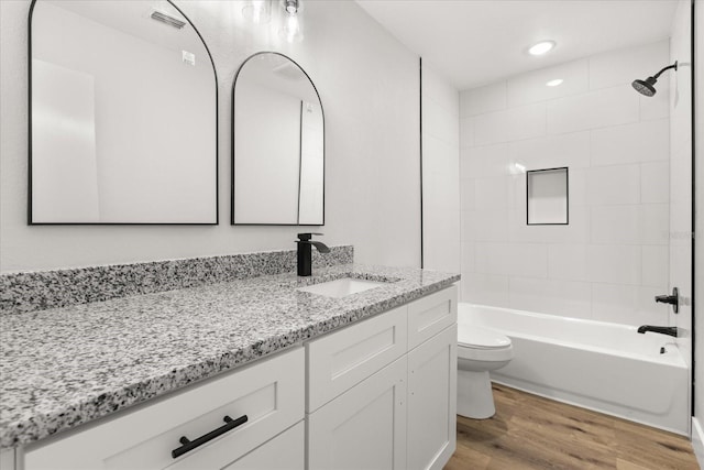 full bathroom with tiled shower / bath combo, wood-type flooring, vanity, and toilet