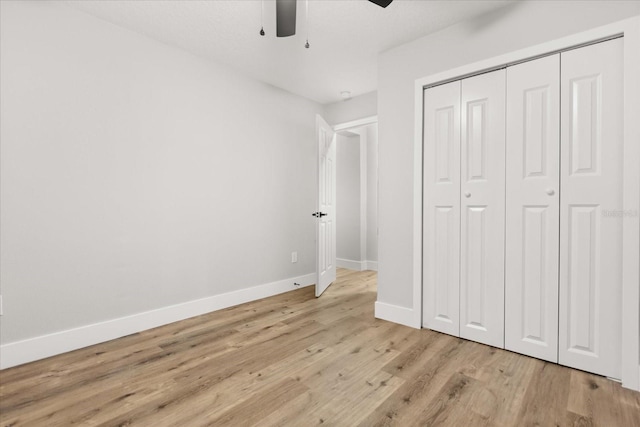 unfurnished bedroom featuring ceiling fan, a closet, and light wood-type flooring