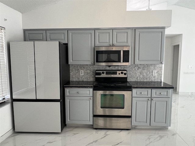 kitchen with tasteful backsplash, appliances with stainless steel finishes, vaulted ceiling, and gray cabinetry